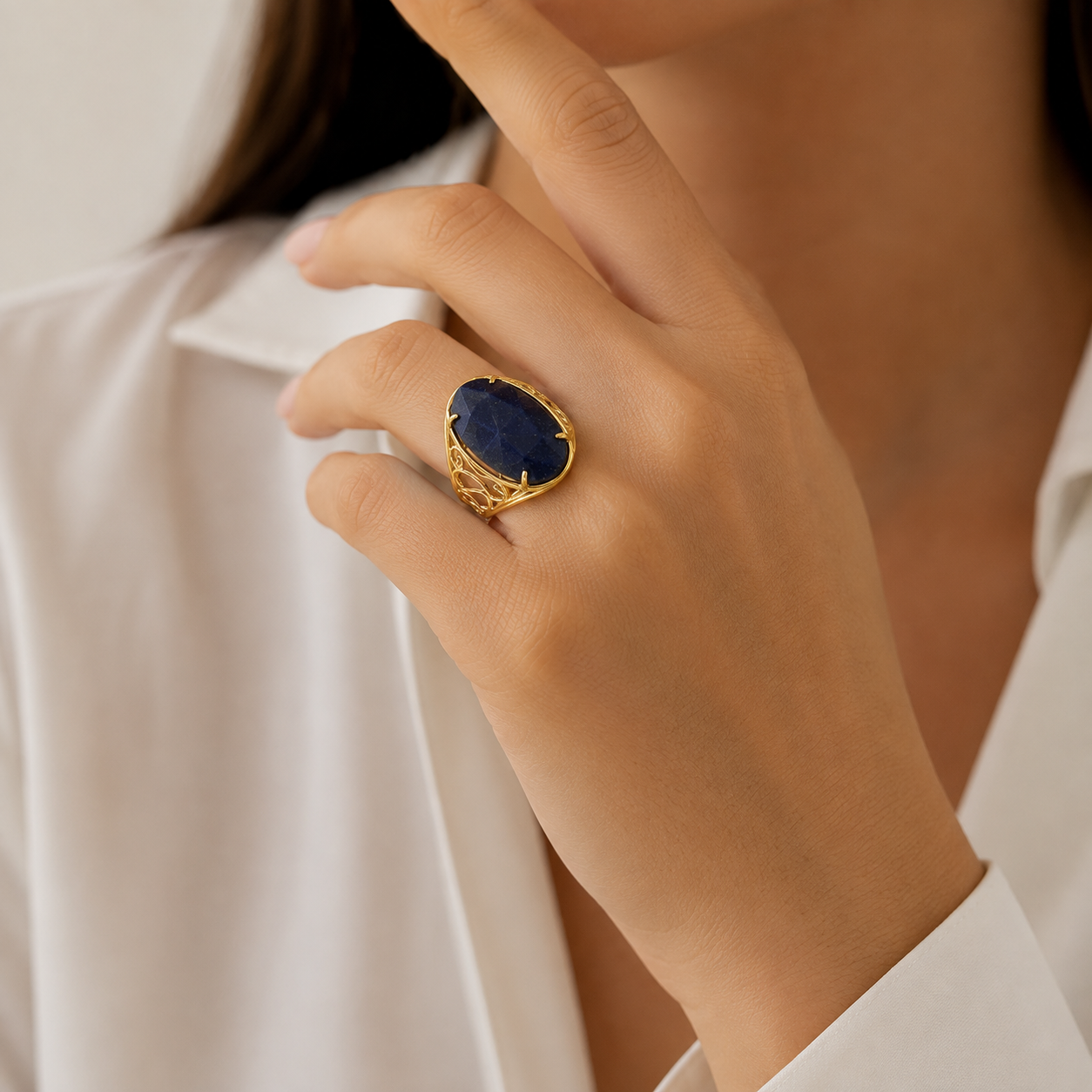 Anillo enchapado en oro de 18K con gema azul profunda y diseño calado dorado en mano de modelo.