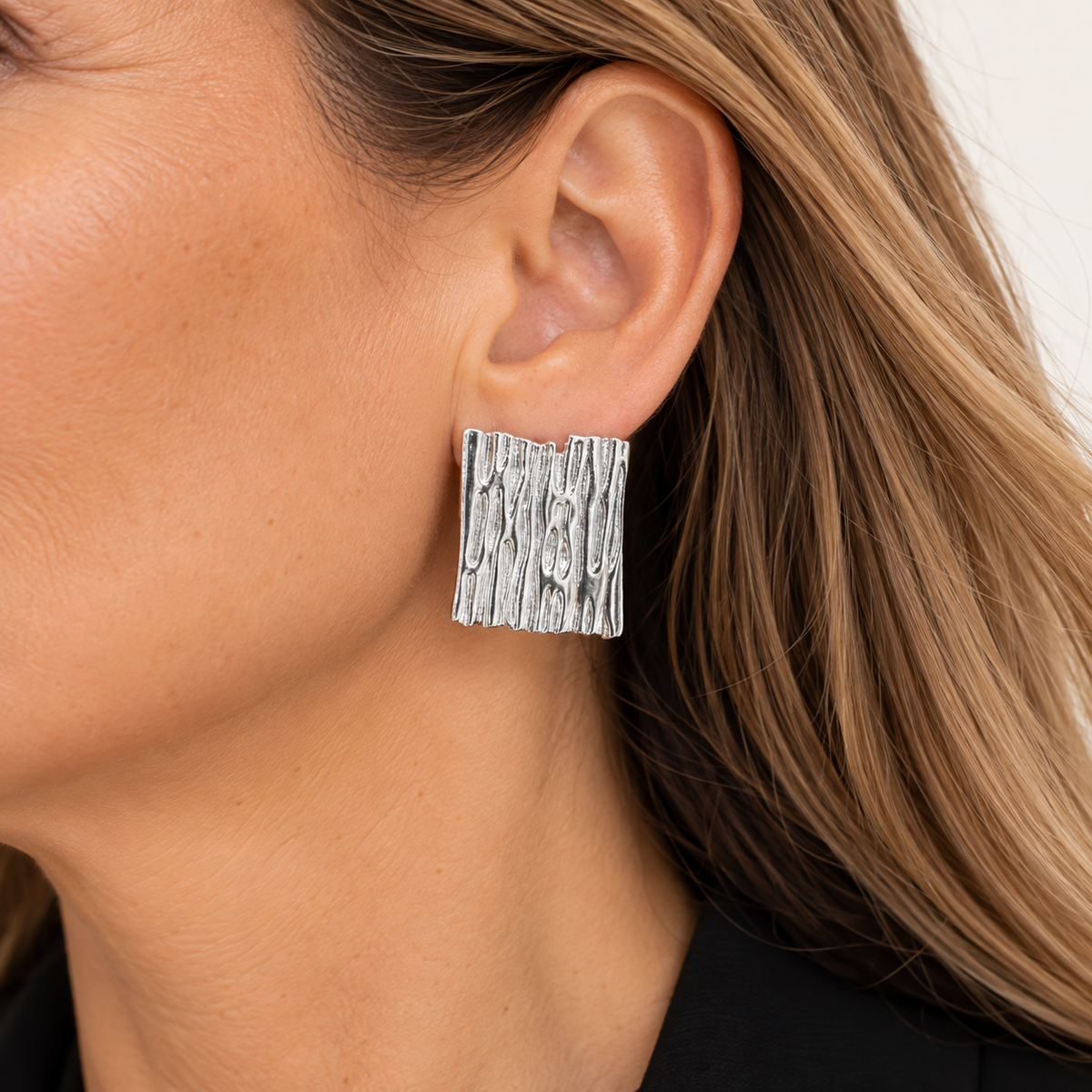 Aro plateado rectangular texturizado MCJoyas puesto en la oreja de una mujer