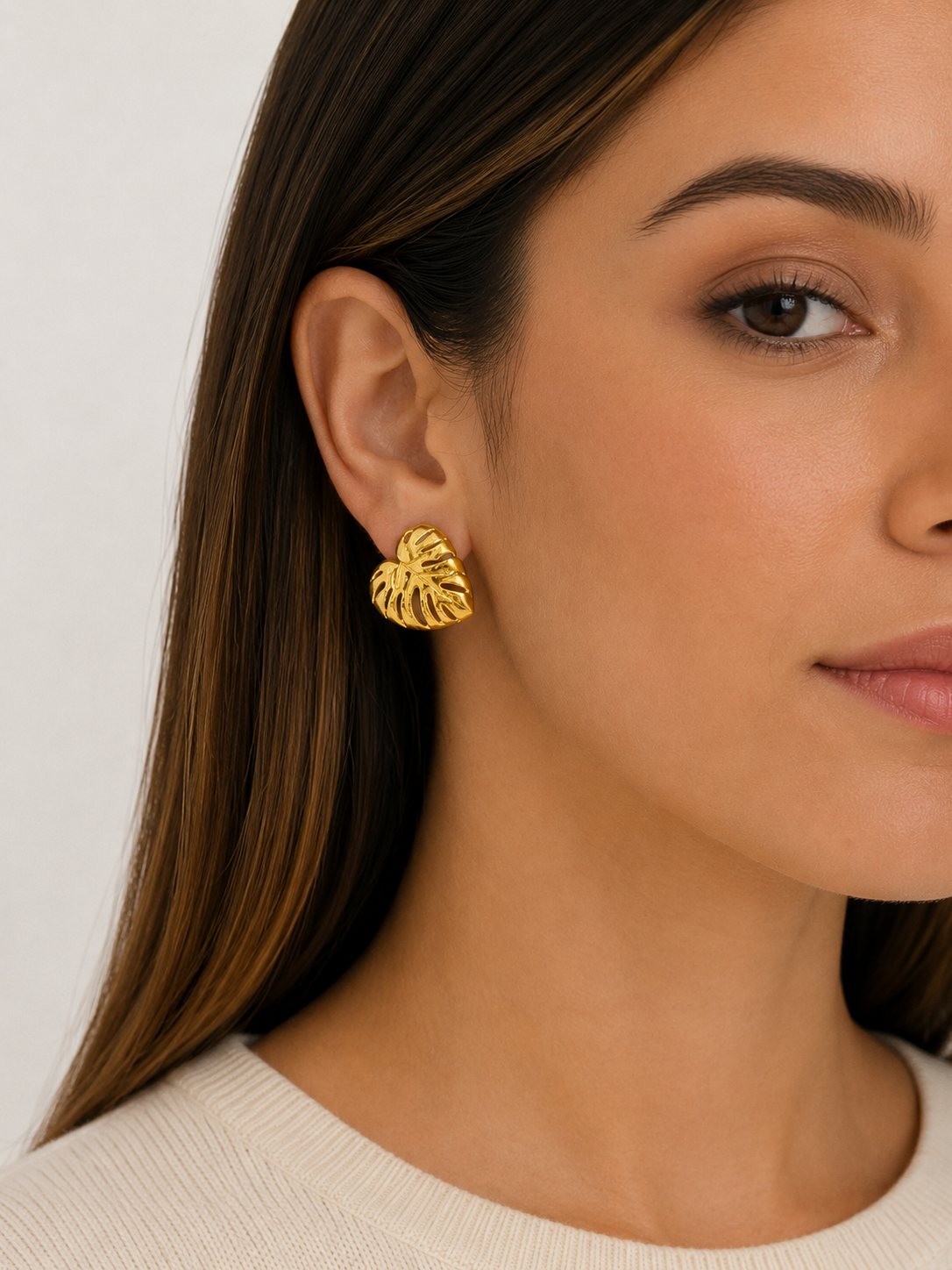 Aros Monstera Dorada de diseño calado en forma de hoja, puestos en modelo