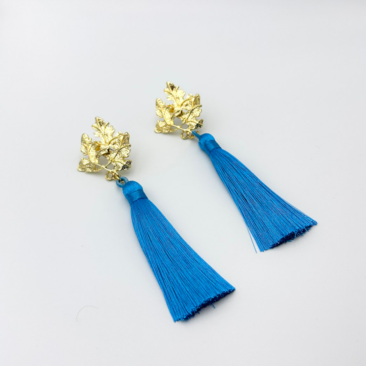 Aros largos con base de hojas doradas y borla azul intenso – MCJoyas..