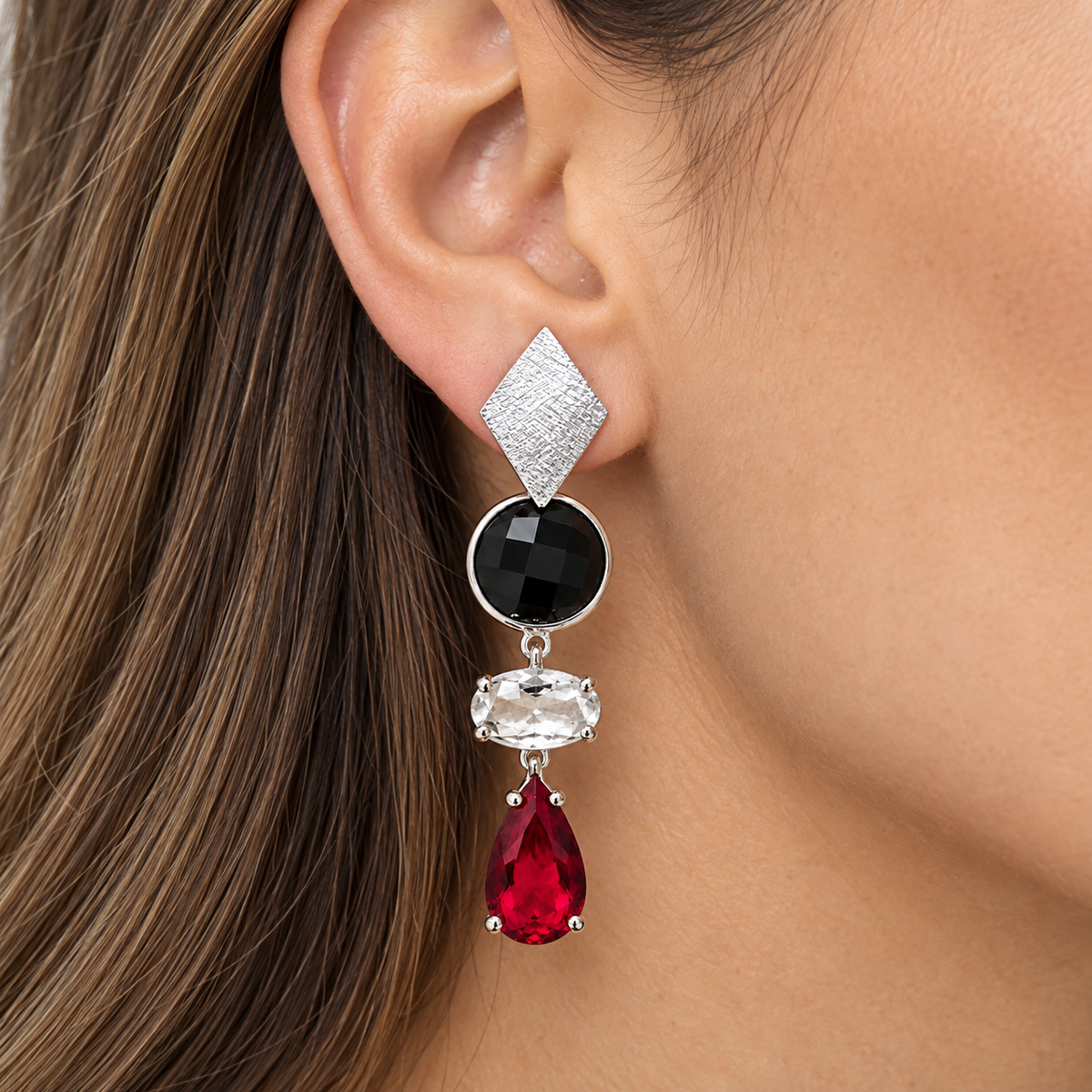 Aros largos plateados con cristales facetados negro, transparente y rojo en forma de gota.