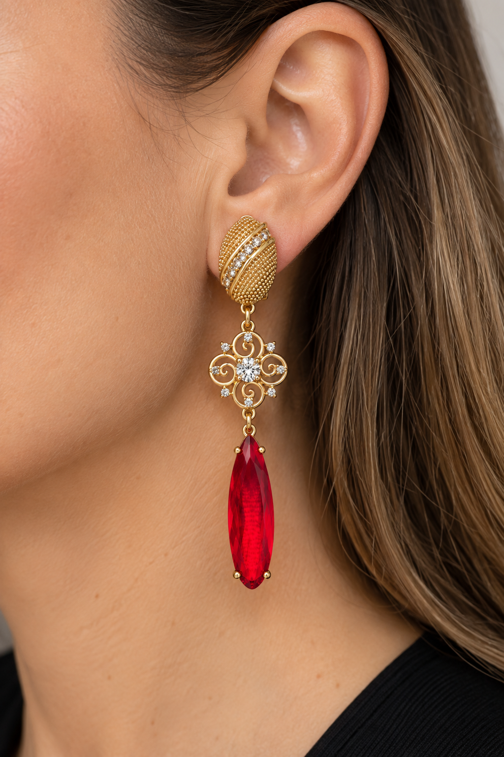 Modelo con vestido negro usando aros largos dorados con cristal rojo de MCJoyas.