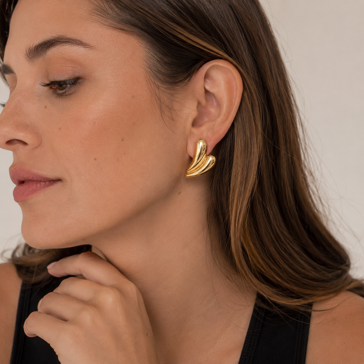 Modelo luciendo Aros Aura Dorada de diseño curvo y acabado dorado brillante.