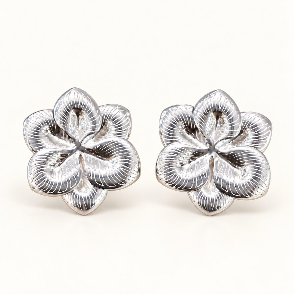 Par de aros clip en forma de flor plateada con pétalos en relieve y líneas grabadas, vista frontal