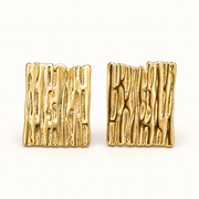 Par de aros clip rectangulares dorados con textura orgánica en relieve, vista frontal